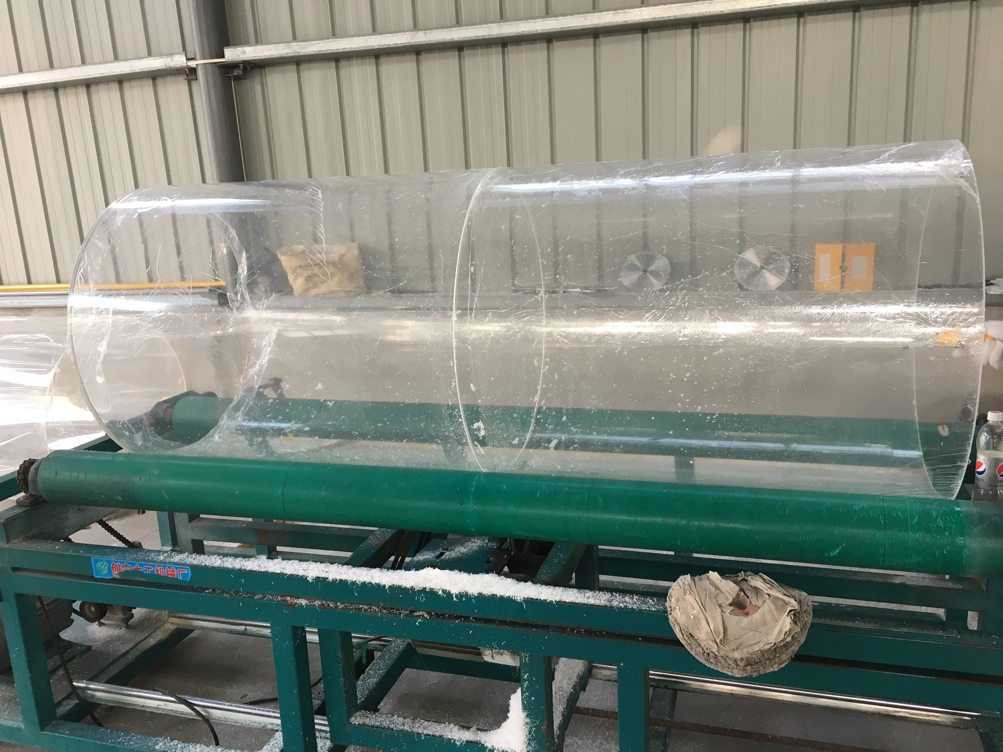 Transparent acrylic cylinder supported on workshop equipment during handling